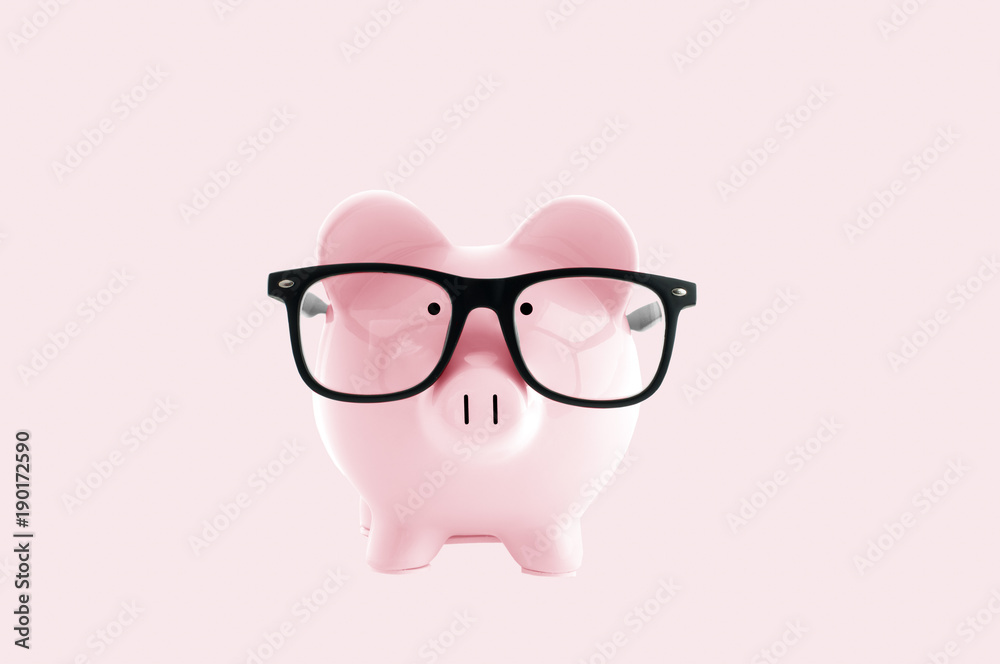 Piggy bank in in glasses on pastel pink background Piggy bank in in glasses on pastel pink background