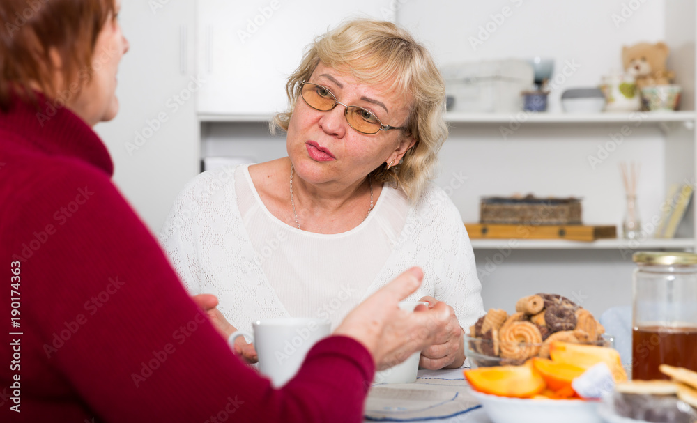 Stressed senior woman talking with female