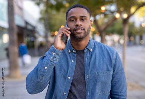 Young black man talking on cell phone walking