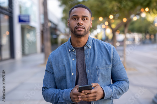 Young black man texting on cell phone walking