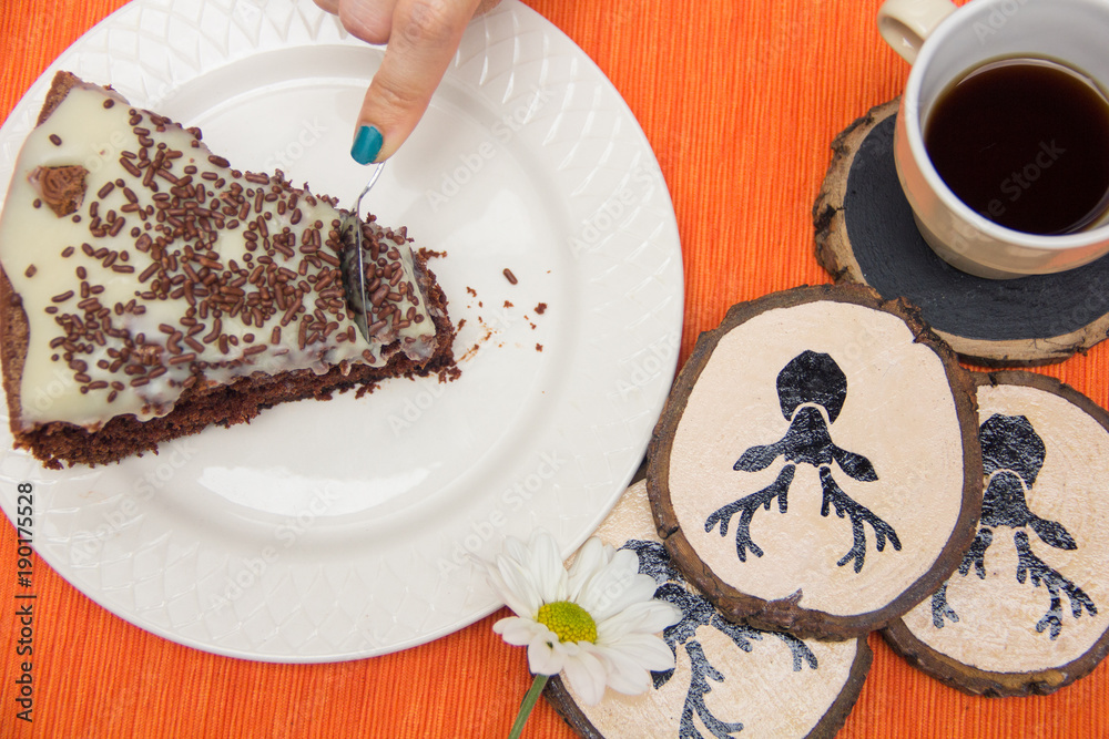 Chocolate cake slice with white chocoalte cream in plate with cup of coffee