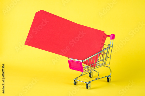 Shopping cart or supermarket trolley and blank red envelop on yellow background with space for add text, Chinese new year and shopping concept.