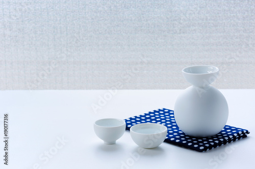 Set for Japanese sake on a napkin with a Japanese pattern on a white table.