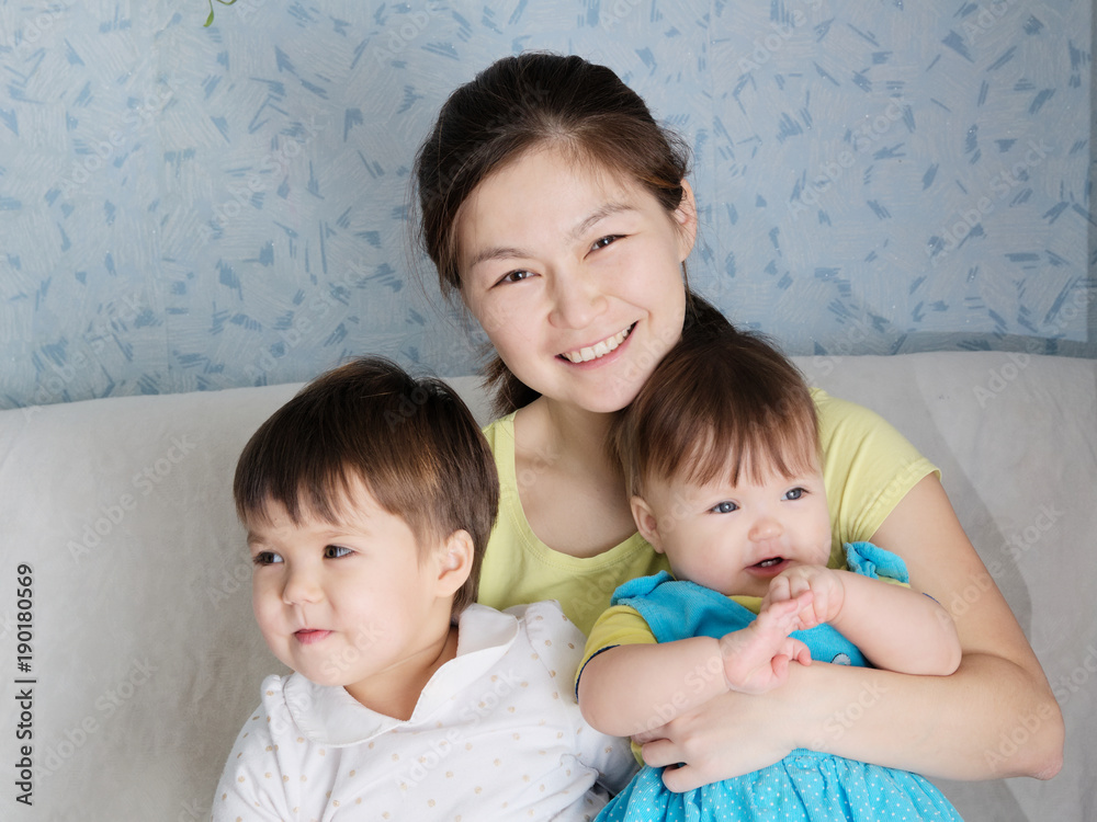 Happy smiling woman with two little girls, multinational family with Asian mother and Caucasian daughters Happy smiling woman with two little girls, multinational family with Asian mother and Caucasian daughters