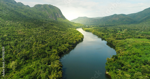 Aerial view of river in tropical green forest with mountains in background photo