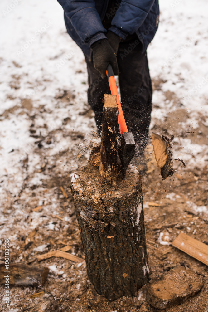 A man chopping wood with an ax in winter A man chopping wood with an ax in winter