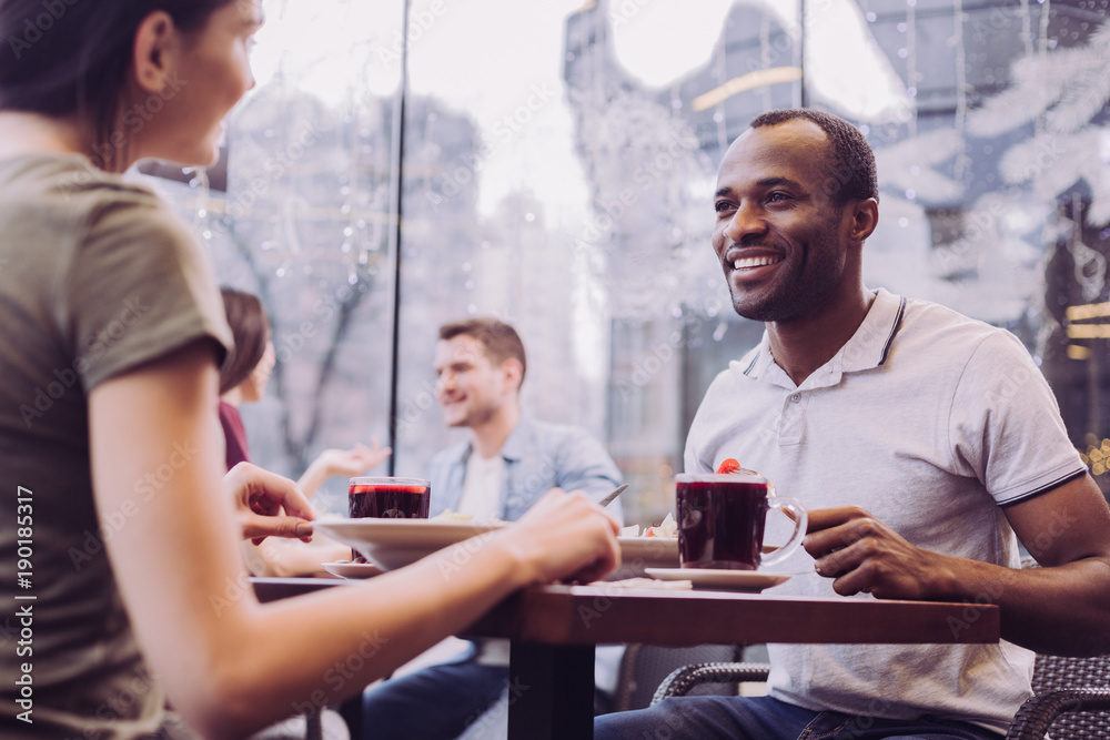 Sweet talk. Low angle of nice handsome positive man sitting at cafe while smiling to woman and staring at her Sweet talk. Low angle of nice handsome positive man sitting at cafe while smiling to woman and staring at her