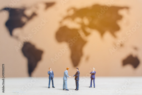 Miniature people :Businessman standing on world map Background