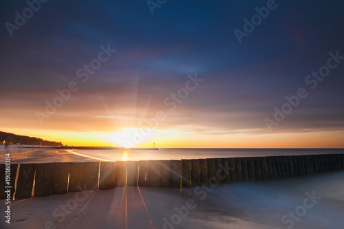 Sunset on the beach with a wooden breakwater, long exposure © dziewul
