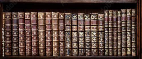 Old books on wooden shelf. Tiled Bookshelf background.