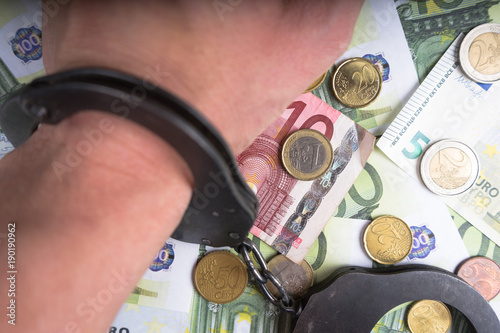 Handcuffs on a pile of euro banknotes. The symbolic meaning of economic crimes. photo