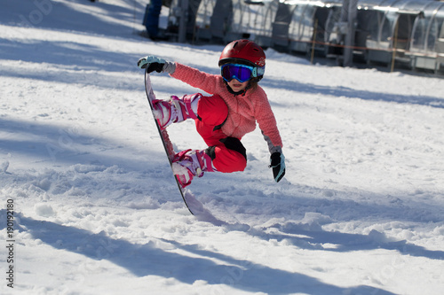 Little Cute Girl Snowboarding  making a tricks at ski resort in sunny winter day. Caucasus Mountains. Mount Hood Meadows Oregon 