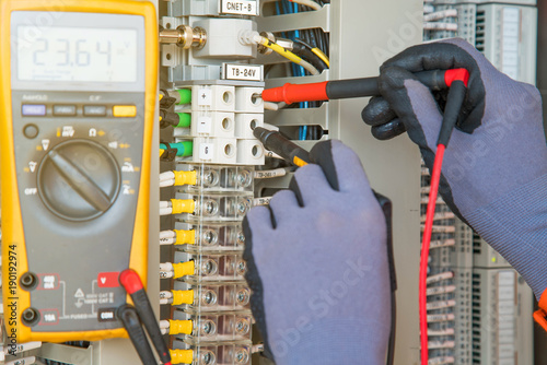 Electrical and instrument technician measuring voltage at electric terminal for troubleshooting electrical system of oil and gas control process, A man using digital multi meter measure volt.