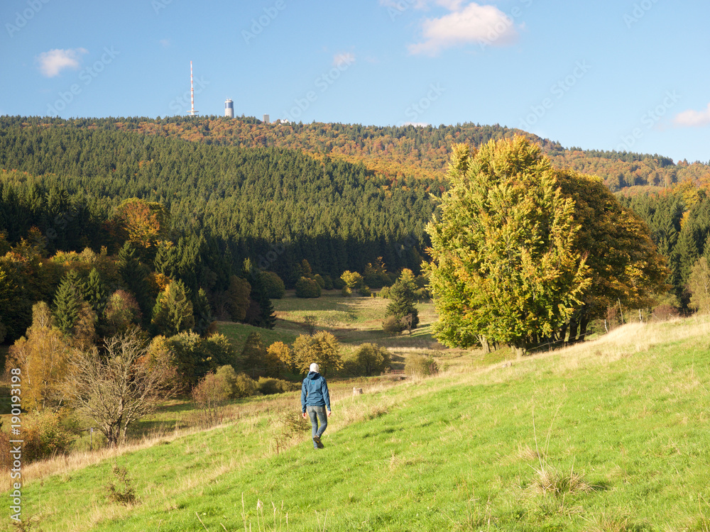 Wanderer im Herbst auf Wiese im Mittelgebirge mit Inselberg