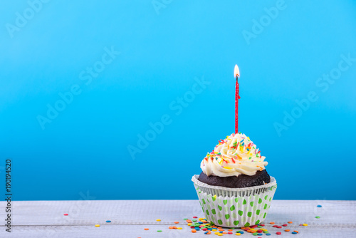 Birthday cupcake on a color background with multicolor candles
