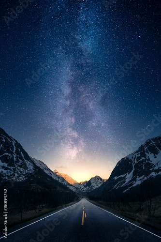 Fototapeta Naklejka Na Ścianę i Meble -  Milky way glowing above a road leading to distance in a mountain valley.