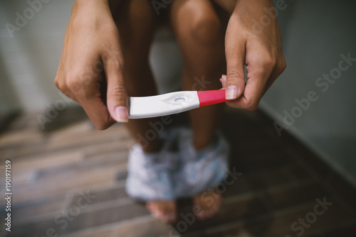 Photo of a pregnancy test in hands of a young girl.