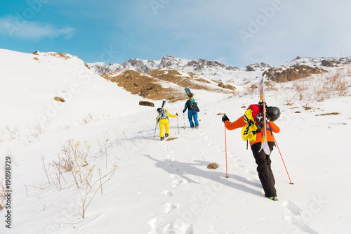 A group of three freeriders climb the mountain for backcountry skiing along the wild slopes of the