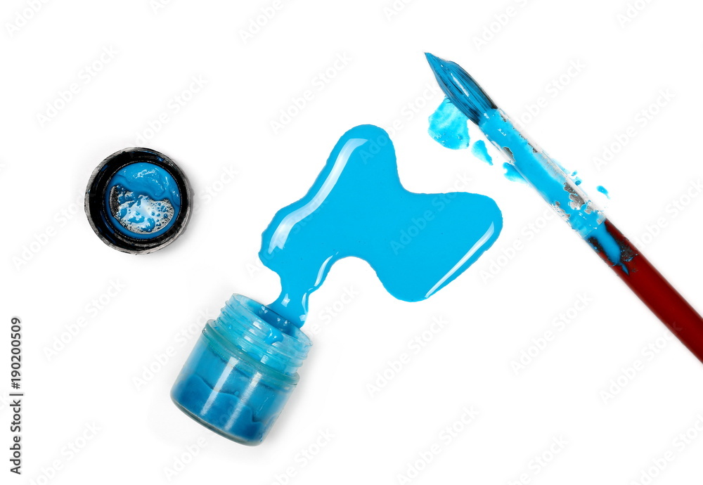 Obraz premium Spilled blue watercolor with bottle and paintbrush isolated on white background, top view