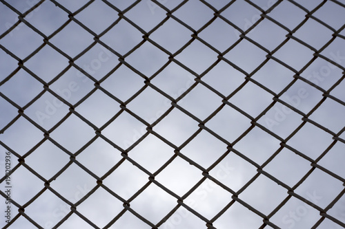 several rows of metal mesh with square cells used as a guard, in the background in the background of the sky the lines from another grid are out of focus