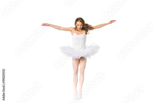 young ballerina with open arms jumping and looking down isolated on white