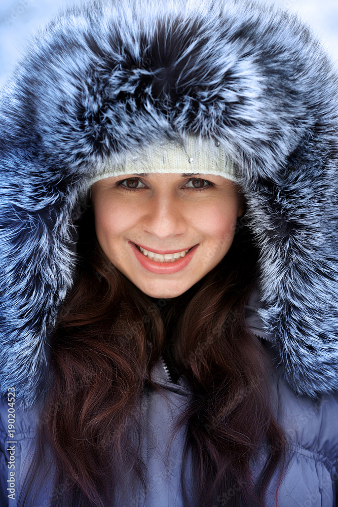 Portrait of a beautiful winter woman in fur hat is walking in the park