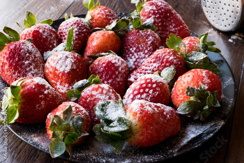 Fresh Organic Ripe Strawberries with Powdered Sugar on Black Plate.
