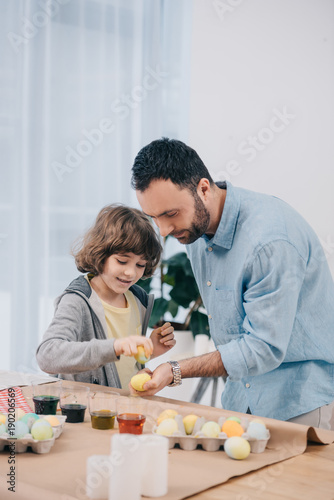 concentrated young father and son painting easter eggs