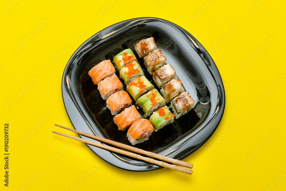 Black plate with various rolls on a yellow background. Top view