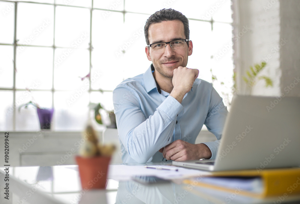 Handsome businessman sitting on his desk in the office