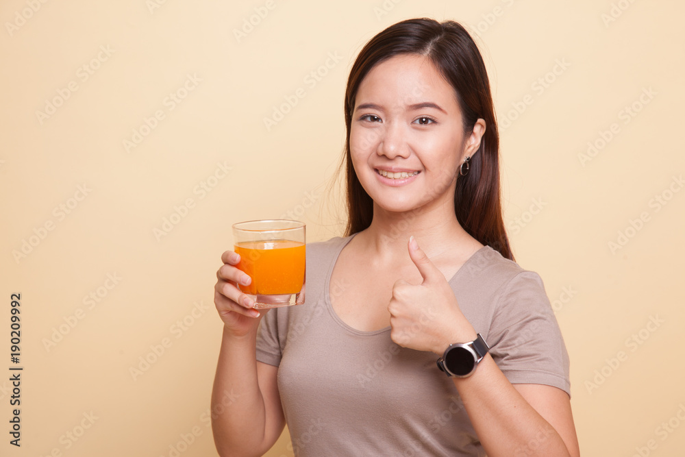 Young Asian woman thumbs up drink orange juice. Young Asian woman thumbs up drink orange juice.
