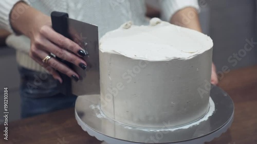 Chef hands frosting the cake with metal spatul photo