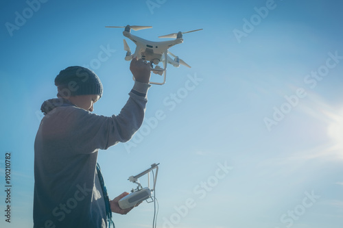 Man operating a drone with remote control. Dark silhouette against colorful sunset. Soft focus.