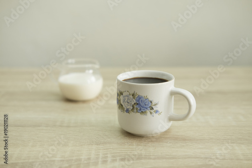 ROSE CERAMIC COFFEE CUP Small rose ceramic coffee cup with milk jar on a wood table.