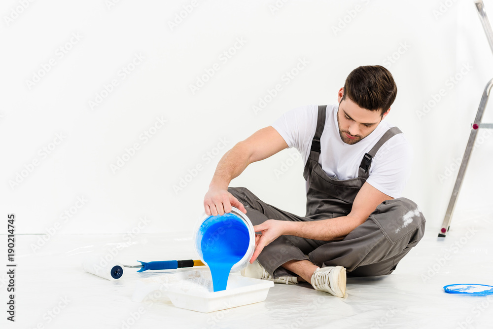 handsome man pouring paint into tray