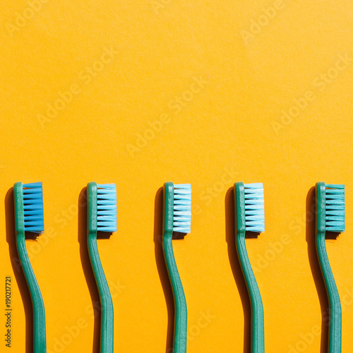 green toothbrushes in row  on yellow with copy space