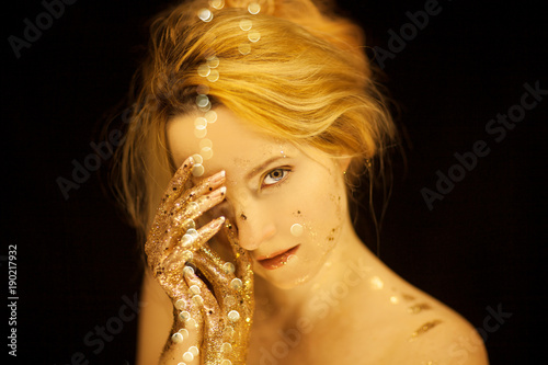 Beautiful woman in gold, golden hands, glitter sensual glamour studio shoot