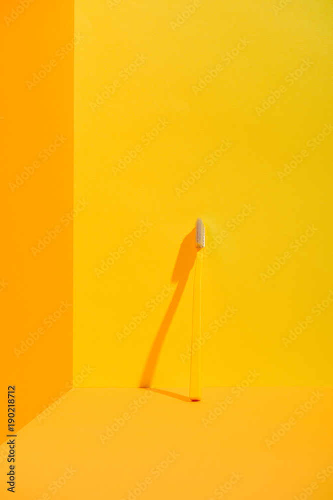 yellow toothbrush standing at orange wall yellow toothbrush standing at orange wall