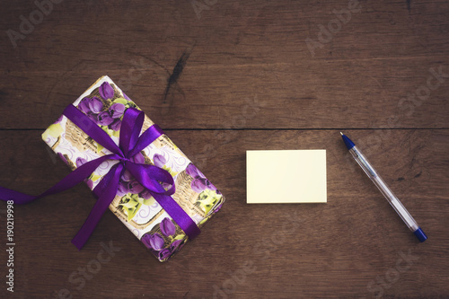 gift box with purple ribbon and floral paper with empty card and  pen