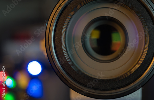 The photo or videocamera lens on dark background with lense reflections