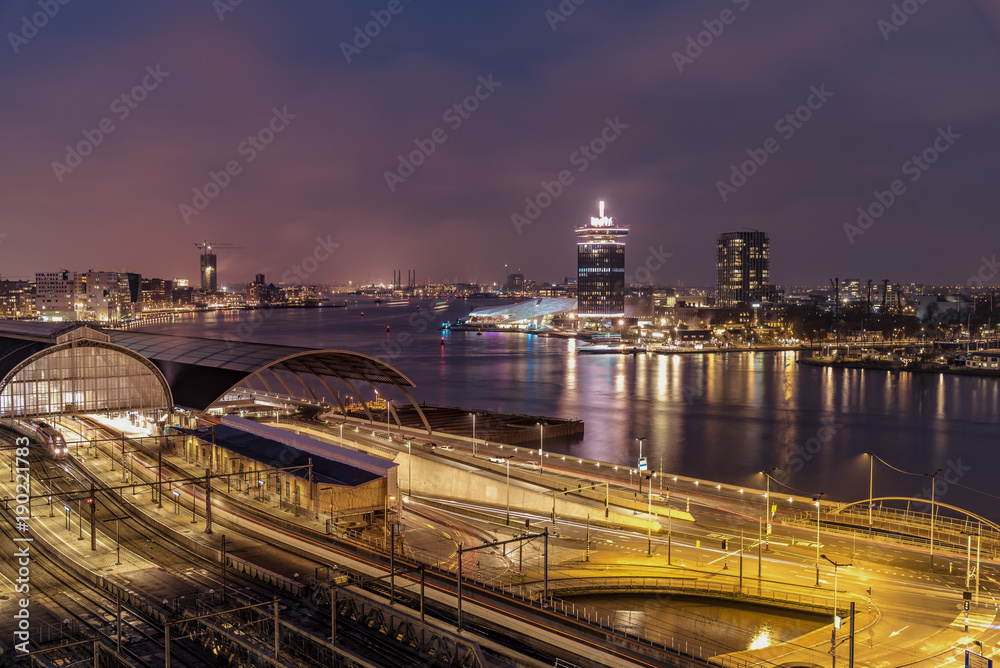 View of the Amsterdam train station and the Amstel river at night, Netherlands