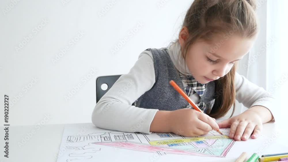 Little girl drawing a picture on white room. 7 years old girl drawing and coloring on a paper at home. Little girl drawing a picture on white room. 7 years old girl drawing and coloring on a paper at home.