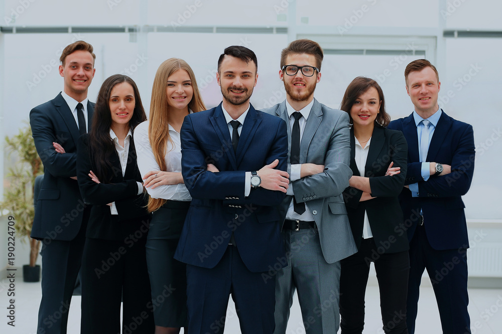 Smiling and confident business team standing in front of a bright window. Smiling and confident business team standing in front of a bright window.