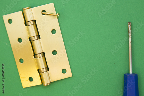 Home, House Repair, Redecorating, Renovating Concept. A door hinge and a screwdriver, green background with copy space, top view, flat lay photo