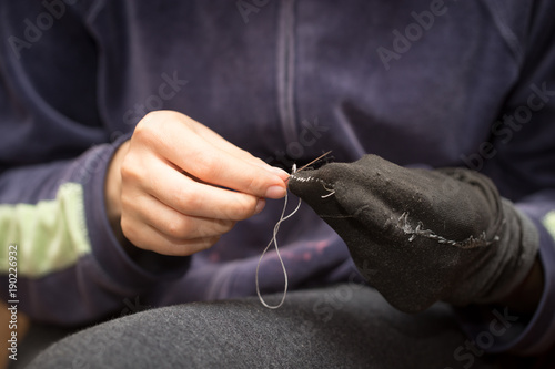 A girl sews a sock with a needle