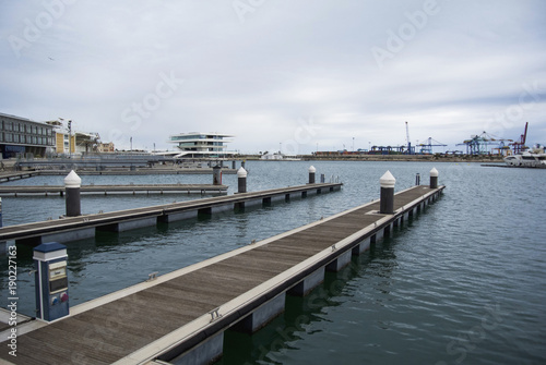 Empty docks in Valencia port, Spain. Valencia Port At Mediterranean Sea. Reflexion in the water. Empty docks in the Spanish port of Valencia in the beginning of spring. Cloudy sky.
