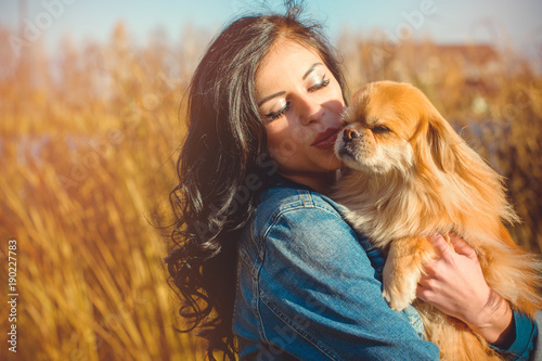 Young woman with her dog walking in the forest at sunny spring day