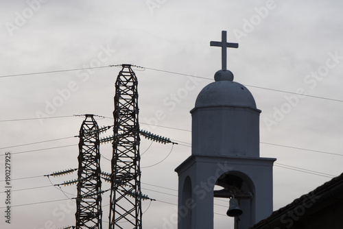 a particolar view of tower and a church with cross photo