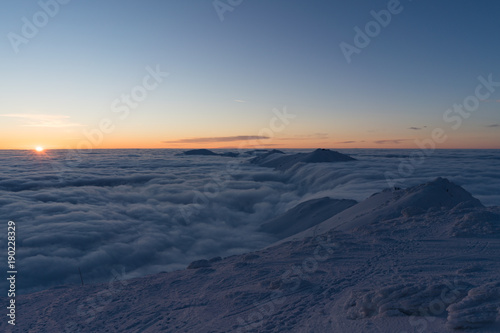 Beautiful sunset above clouds in snow covered Low Tatras mountains during susnet in winter