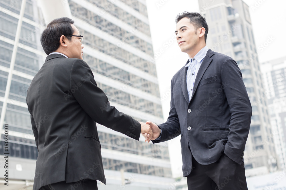 Successful negotiating business concept, Businessmen shaking hands after finishing meeting or setting goals and planning way to success in front of building . Successful negotiating business concept, Businessmen shaking hands after finishing meeting or setting goals and planning way to success in front of building .